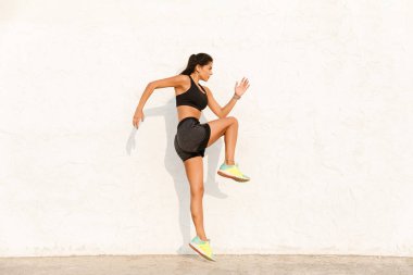 Tam boy görüntü güzel kız 20'li spor yapıyor ve duvardan vücudu germe eşofman