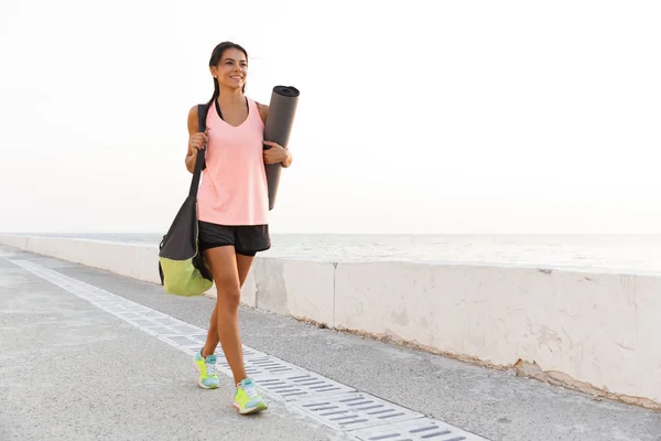 Smiling Young Sportswoman Holding Fitness Mat Walking Outdoors Seaside — Stock Photo, Image