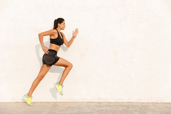 20岁的健康女孩穿着运动服在墙壁上跑来跑去的全貌 — 图库照片
