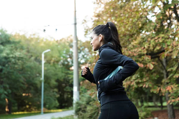 Vista Lateral Una Joven Mujer Fitness Confiada Corriendo Parque Escuchando — Foto de Stock