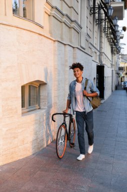 Bisiklet ile açık havada sokakta dolaşan mutlu genç Afrika adam görüntüsünü.