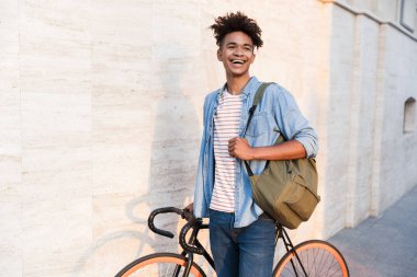 Bisiklet ile açık havada sokakta dolaşan mutlu genç Afrika adam görüntüsünü.