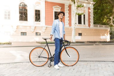 Yakışıklı duygusal genç Afrika adam açık havada bisiklet ile yürüyüş sokak görüntüsünü.