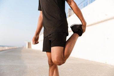 Güçlü bir genç adam sporcu yapmak egzersizleri açık havada sahilde kırpılmış görüntü.