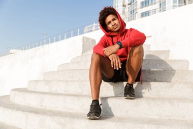 Genç bir adam açık havada poz basamaklarında oturan sahilde görüntüsünü.