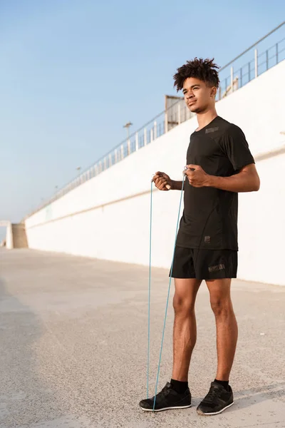スキップ ロープ屋外ビーチに立っているハンサムな若い男スポーツマンのイメージ — ストック写真