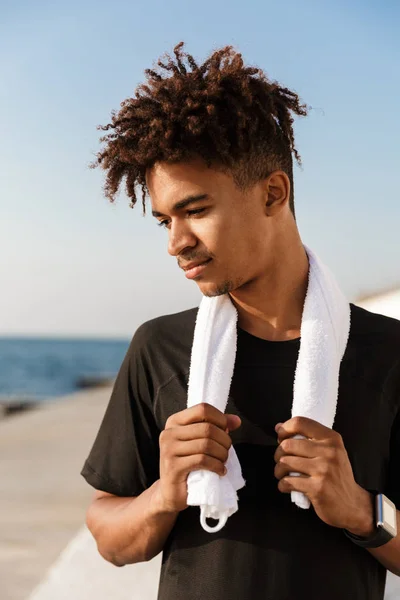 タオルを保持してビーチの屋外の若い男スポーツマンの写真 — ストック写真