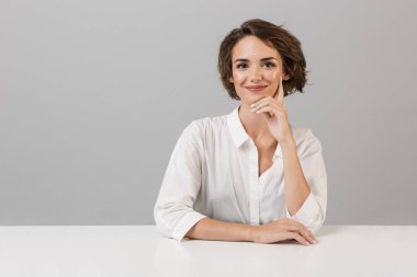 Masada oturan gri duvar arka plan üzerinde izole görüntüsünü poz genç iş kadını.