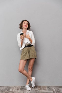 Güzel kadının 20s tam boy görüntü gülümseyen ve paket servisi olan restoran kahve gri arka plan üzerinde izole holding