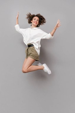 Tam boy görüntü olumlu kız gülümseyerek ve atlama 20s gri arka plan üzerinde izole