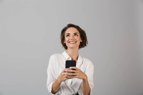 使用手机聊天的快乐年轻女商人在灰色墙壁背景被隔离的图片 — 图库照片
