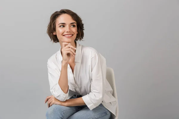 スツールに座っている灰色の壁背景を分離した若いビジネス女性がポーズの画像 — ストック写真