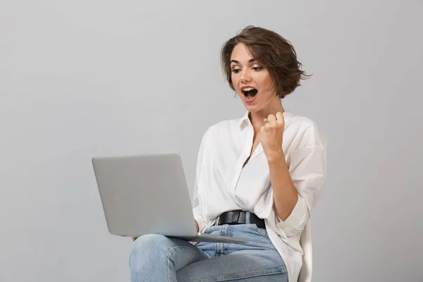 Photo Shocked Happy Young Woman Sitting Stool Isolated Grey Background — Stock Photo, Image