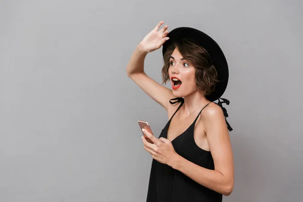 Foto Mujer Encantadora Años Con Vestido Negro Sombrero Sosteniendo Teléfono —  Fotos de Stock