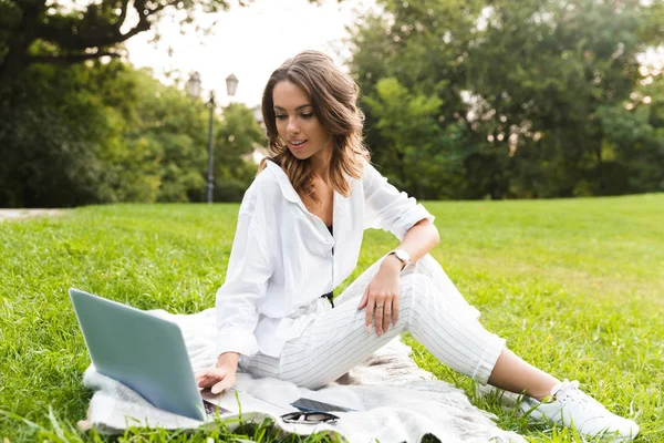 Dizüstü Bilgisayar Kullanan Bir Çim Üzerinde Oturan Parkta Genç Kadın — Stok fotoğraf