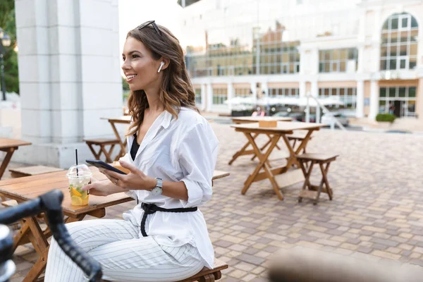 Jonge Vrouw Oortelefoons Zit Het Café Open Lucht Met Behulp — Stockfoto