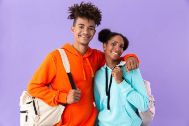 Menekşe arka plan üzerinde fotoğraf çekici Afro-Amerikan kardeşi ve kız kardeşi birlikte sarılma sırt çantaları giyen izole