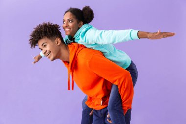 Menekşe arka plan üzerinde izole kız arkadaşı piggybacking güzel Afrikalı-Amerikalı adam fotoğrafı
