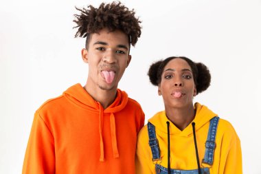 Eğleniyor ve beyaz arka plan üzerinde izole kamera dilini gösteren renkli giysiler içinde eğlenceli Afro-Amerikan çift