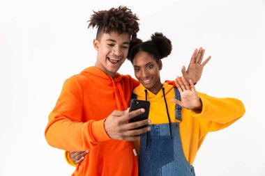 Genç Afro-Amerikan çift renkli giysiler selfie fotoğrafta beyaz arka plan üzerinde izole cep telefonuyla fotoğraf