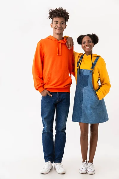 Full length photo of joyful african american brother and sister in colorful clothes smiling while standing together isolated over white background