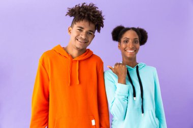 Güzel bir Afrikalı-Amerikalı kadın işaret parmağı bir kenara yakışıklı adama menekşe arka plan üzerinde izole fotoğrafı
