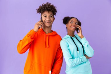Neşeli Afrikalı-Amerikalı adam ve birlikte cep telefonu menekşe arka plan izole konuşurken kız fotoğrafı