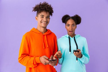 Genç Afro-Amerikan çocuk ve menekşe arka plan üzerinde izole akıllı telefonlar kullanan kız fotoğrafı