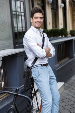 İşadamı gülümseyen gömlek açık havada bir bisiklet yaslanmış bir çanta taşıyor şehir sokak ayakta giyinmiş