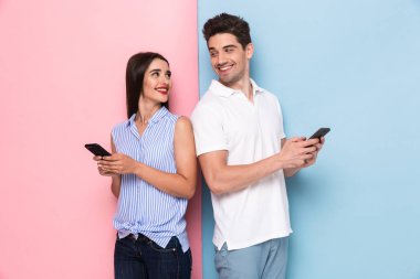 İyimser çift cep telefonları birlikte izole renkli arka plan üzerinde kullanma