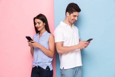 Gülümseyen çift cep telefonları birlikte izole renkli arka plan üzerinde kullanma