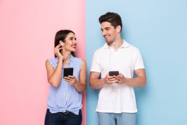 Çekici bir adam ve kulaklık giyen ve renkli arka plan üzerinde izole akıllı telefonlar kullanan kadın görüntüsü