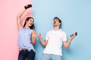 Heyecanlı adam ve müzik cep telefonları renkli arka plan üzerinde izole kulaklık giyen kadın görüntüsü