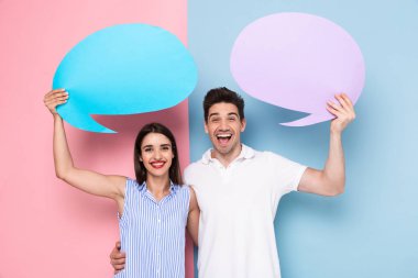 Görüntü neşeli adam ve renkli arka plan üzerinde izole duyuru için boş kabarcıklar tutan kadın