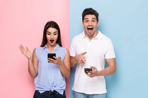 Bild Glada Mannen Och Kvinnan Fritidskläder Håller Mobiltelefoner Isolerade Över — Stockfoto