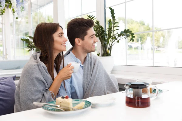 カフェに座っている驚くべき若い夫婦のイメージを食べるデザートとお茶を飲みながら — ストック写真