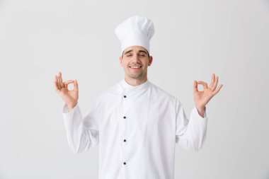 Görüntü izole kapalı beyaz duvar arka plan üzerinde yakışıklı genç şef meditasyon.