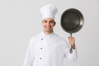 Görüntü izole kapalı kızartma tavası holding beyaz duvar arka plan üzerinde heyecanlı duygusal genç adam şef.