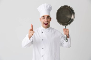 Görüntü izole kapalı kızartma tavası holding beyaz duvar arka plan üzerinde heyecanlı duygusal genç adam şef.
