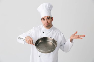Görüntü izole kapalı kızartma tavası holding beyaz duvar arka plan üzerinde karışık genç adam şef.