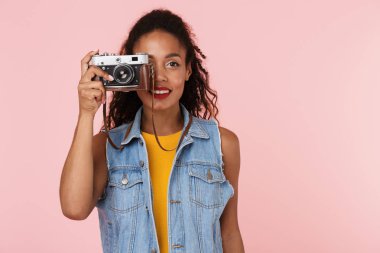 Güzel genç Afrikalı kadın kamera tutarak pembe backgroung duvardan izole görüntüsünü.