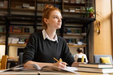Dalgın kırmızı saçlı Genç kız Kütüphane tabloda öğrenim