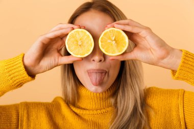 Sarı duvar arka plan üzerinde izole gözlerle narenciye limon poz kapsayan bir güzel kadın fotoğrafı.