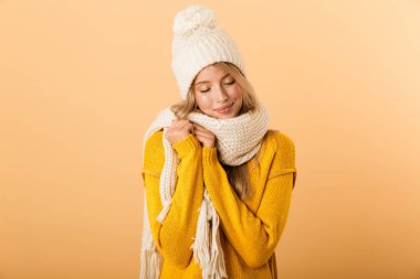 Atkı ve şapka sarı duvar arka plan üzerinde izole poz mutlu sevimli kadın fotoğrafı.