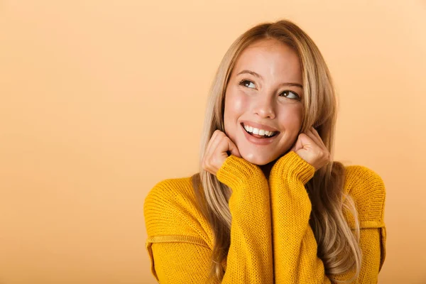 黄色の背景で離れて見て 彼女の顔を手を繋いで立って分離セーターに身を包んだ幸せな若い女の肖像 — ストック写真
