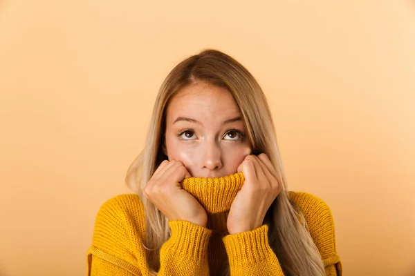 分離に立って見上げるセーターに包まれた 黄色の背景のセーターに身を包んだ怖がって若い女性の肖像画 — ストック写真