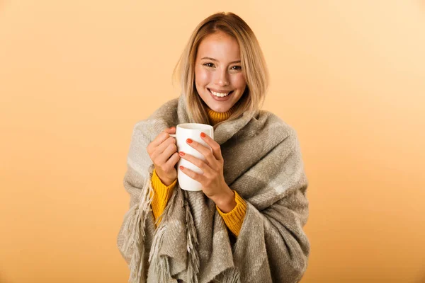 お茶のカップを保持している黄色の壁の背景に分離された格子縞の幸せな女の写真 — ストック写真