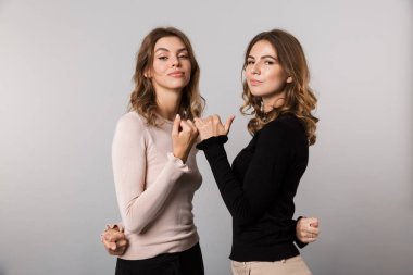 Görüntü gülümseyen ve birbirlerinin küçük parmaklar uzlaşma veya gri arka plan üzerinde izole dostluk çengel iki güzel kadın