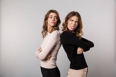 Görüntü arka arkaya silah ile iki üzgün kadının geçti ve kızgınlık ifade izole gri arka plan üzerinde