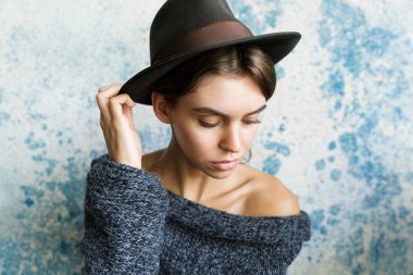 Mavi duvar arka plan üzerinde kazak ve şapka giymiş genç bir kadın portresi yakın poz